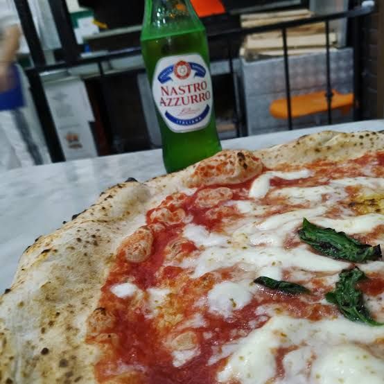 A pizza topped with cured pork and rosemary, close up.