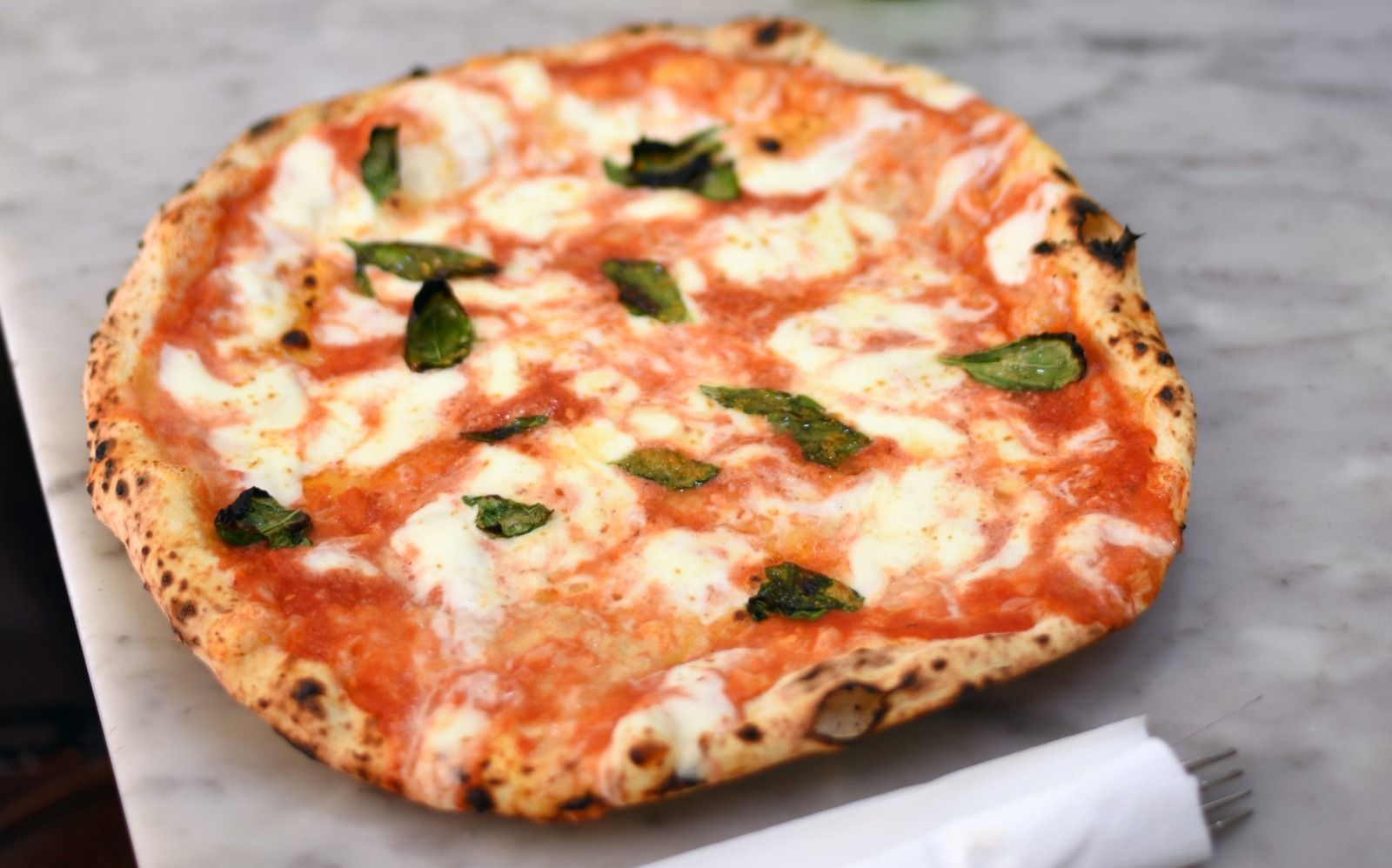 A pizza on a table with diners out of focus behind it.