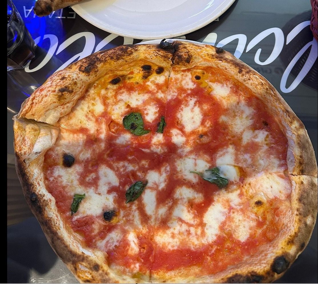 Several pizzas on a table with people seated around it.