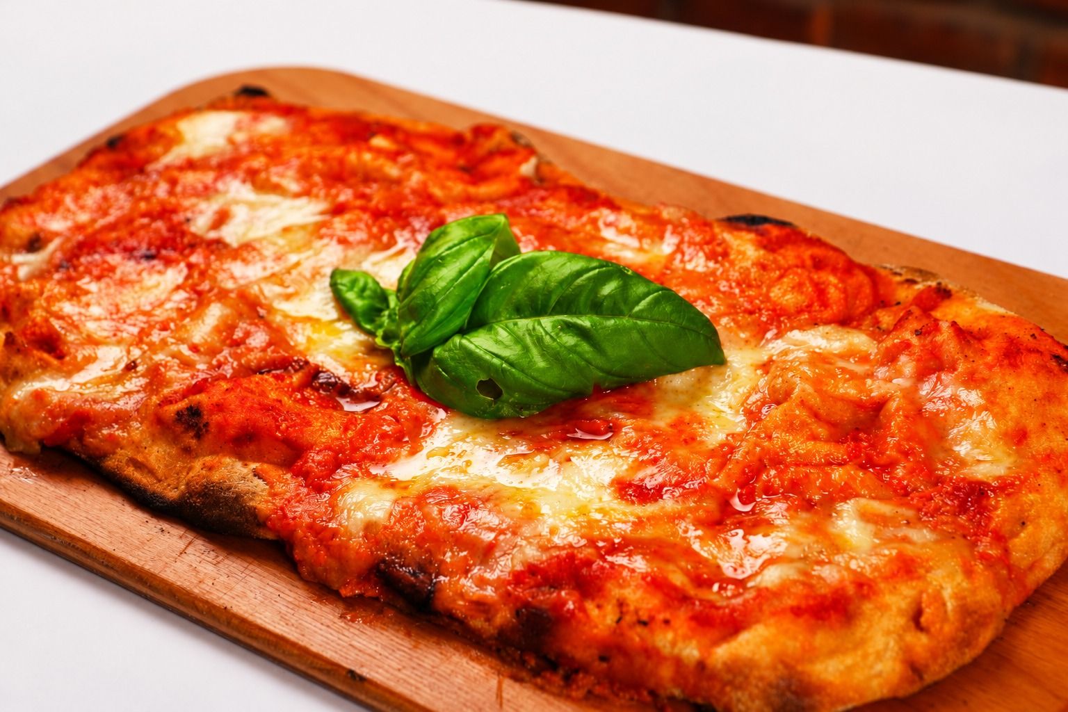 A pizza resting in front of an open oven fire.